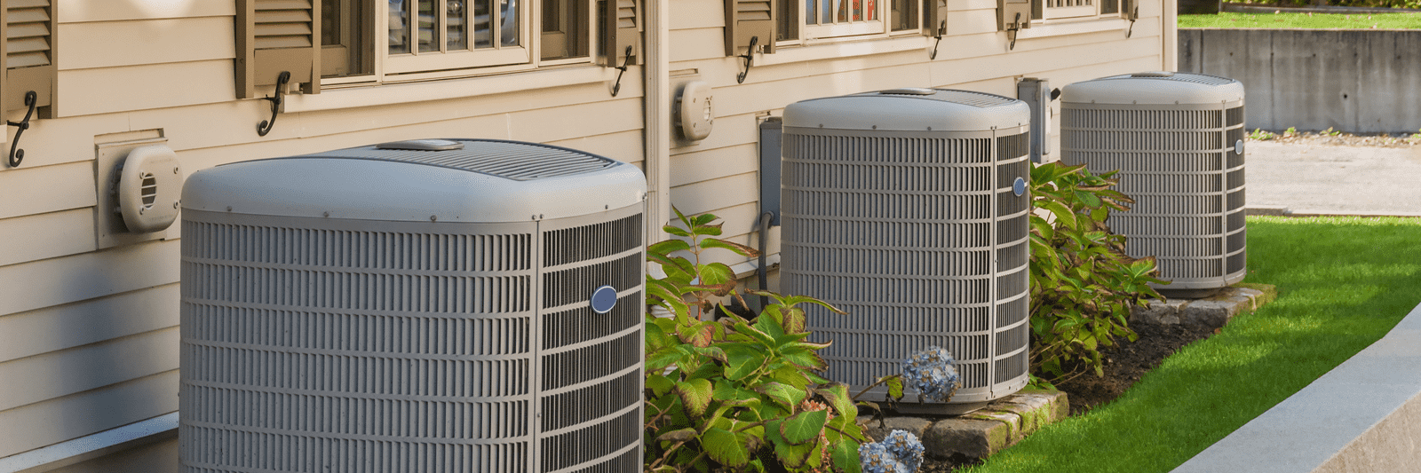 Row of outdoor air conditioner units beside a home