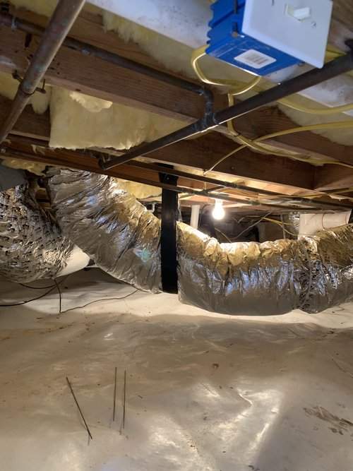 Insulated flex ducts hung from the floor joists of a crawl space