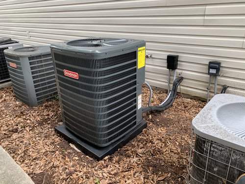 New Goodman outdoor units installed on a mulch bed beside a house