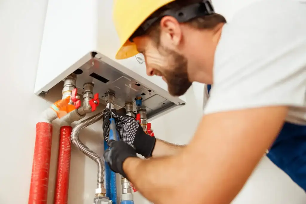 Technician in a hard hat working on the piping under a wall-mounted unit