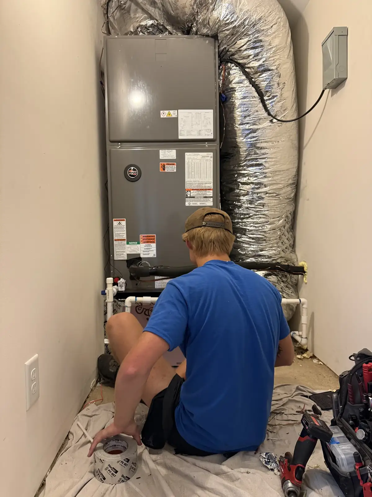 Technician installing an upright air handler in a closet