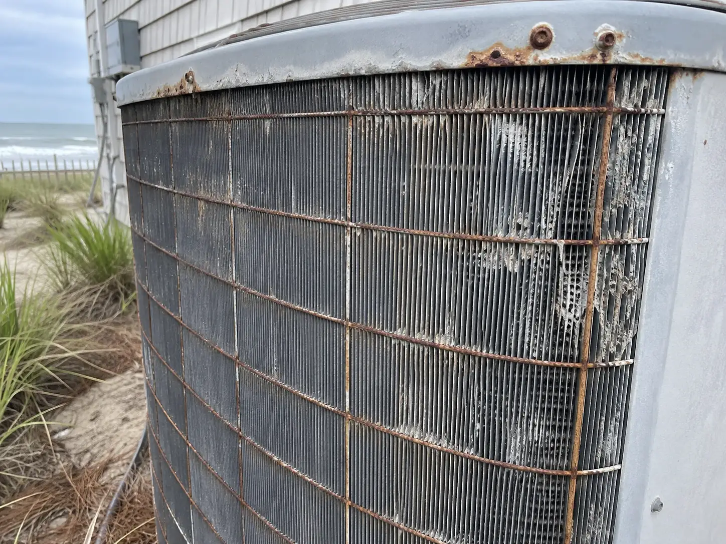 Corroded outdoor AC condenser fins on a coastal Grand Strand home after salt-air exposure